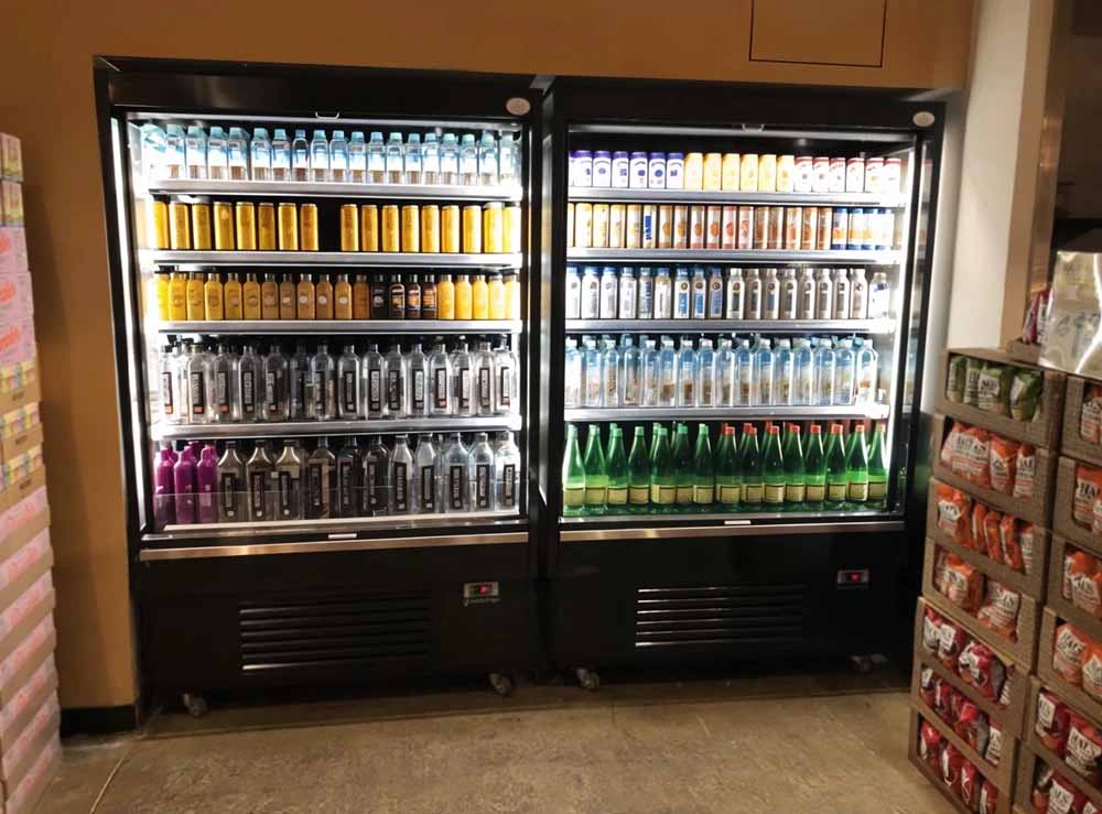 Two glass-fronted refrigerators filled with various drinks, showcasing colourful cans and bottles.