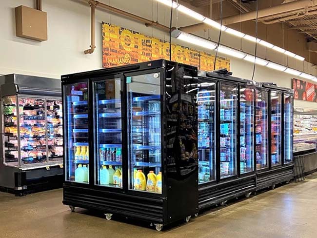 Black triple-door refrigeration units with illuminated shelves, displaying various beverages in a retail setting.