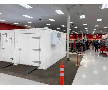 White modular structure in a retail space, with red walls and orange safety cones nearby.